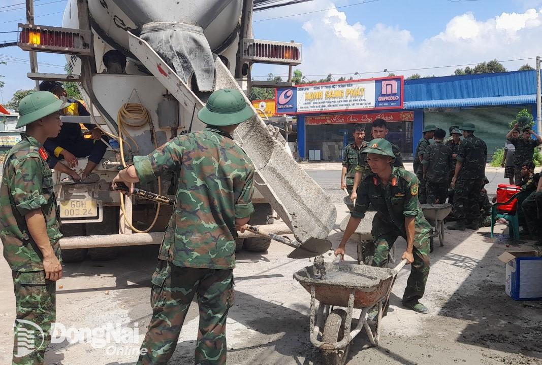 Cán bộ chiến sĩ các đơn vị lực lượng vũ trang giúp dân làm đường bê tông (Ảnh: Ban CHQS H.Long Thành)